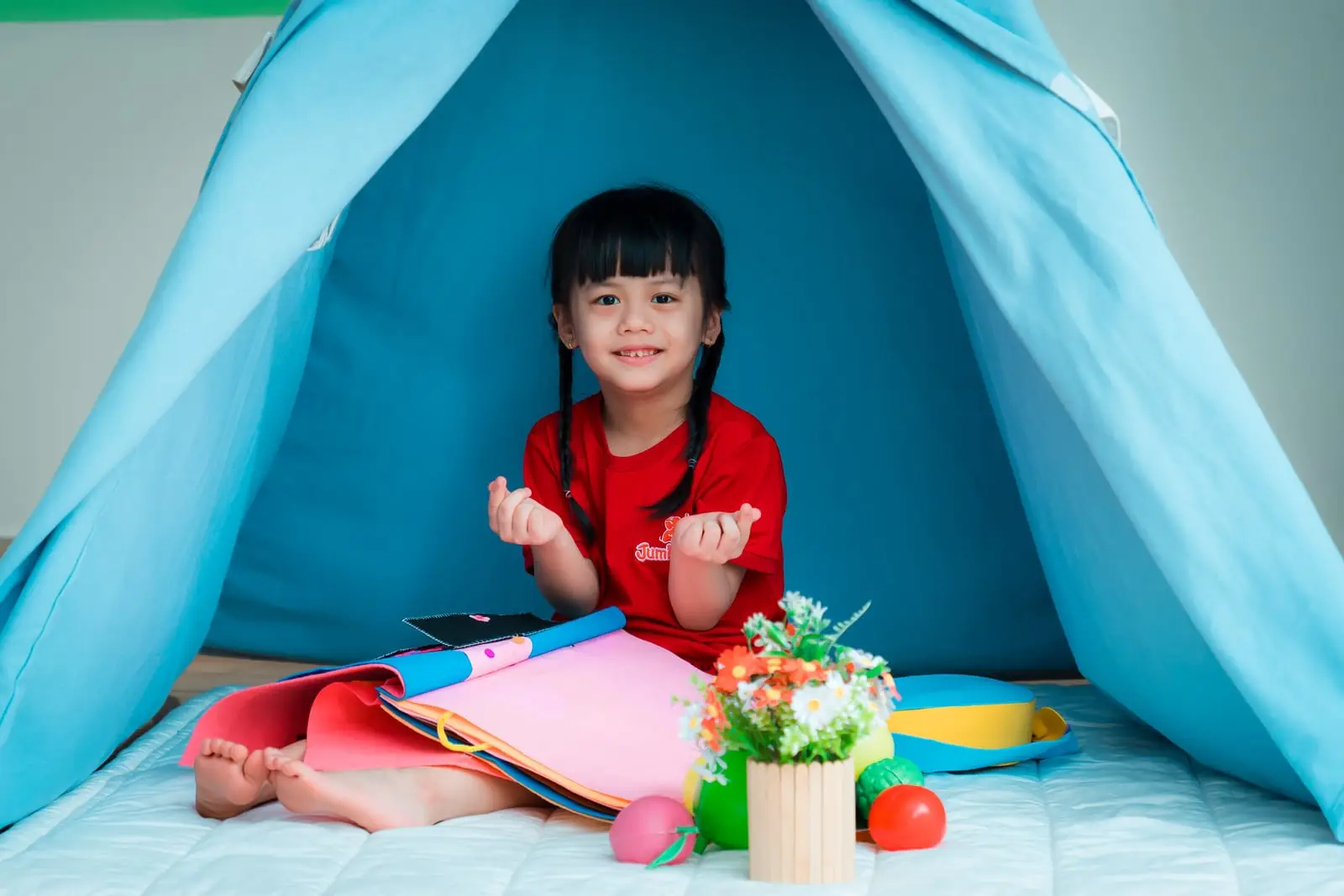 Bé gái ngồi trong lều ở góc đọc sách của lớp