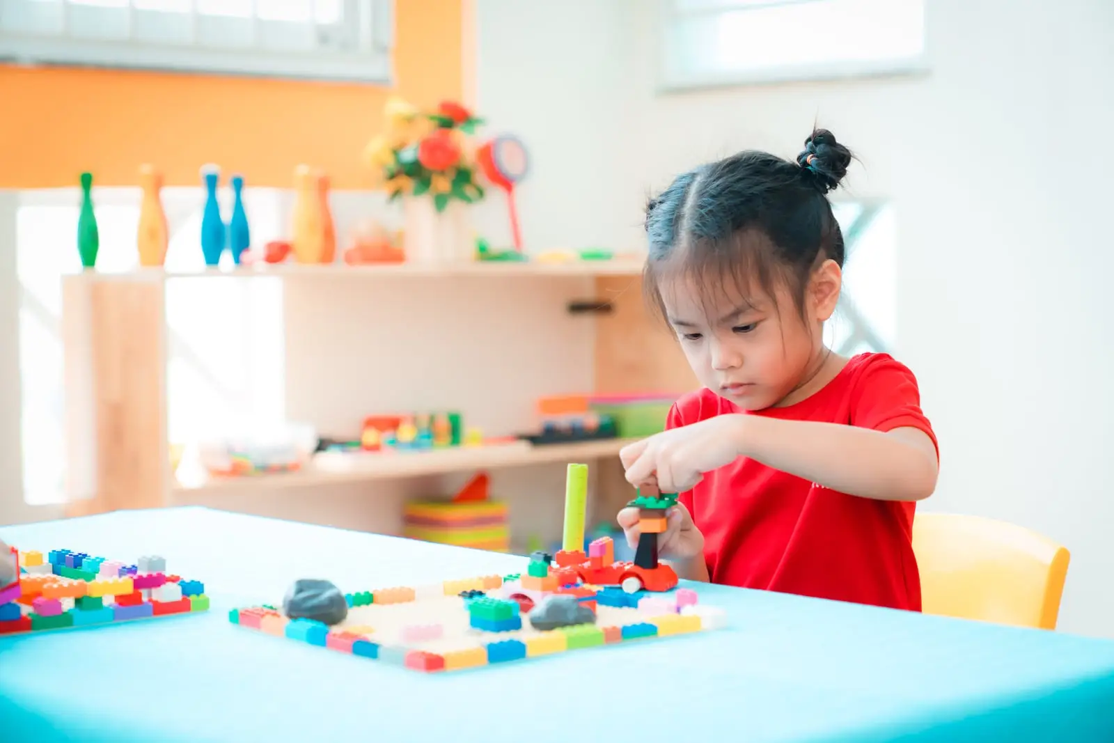 Bé gái chăm chú lắp ghép lego trên bàn trong lớp