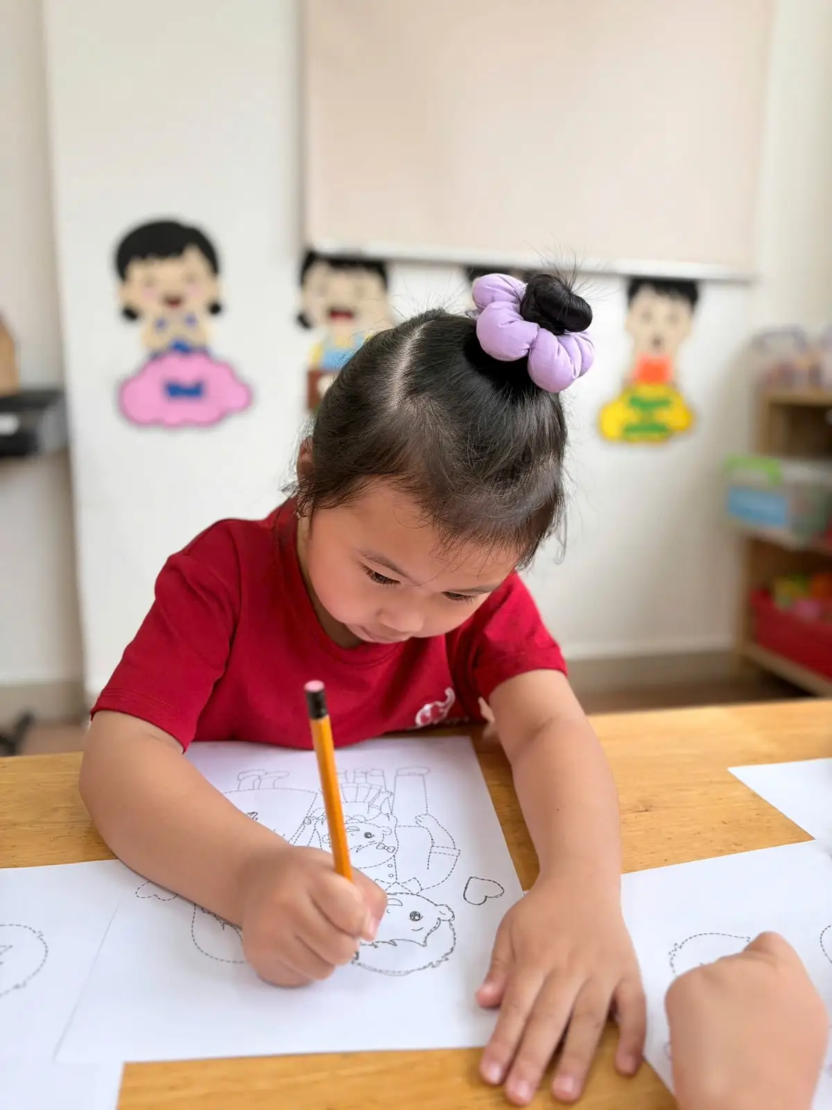 Bé gái lớp Lá cầm bút chì tô nét tranh gia đình