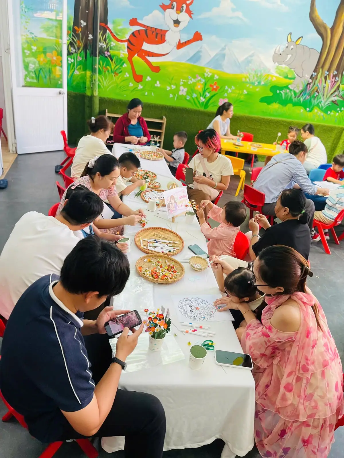 Nhiều gia đình cùng các bé cắm hoa bên bàn dài trong ngày hội 20/10 ở trường