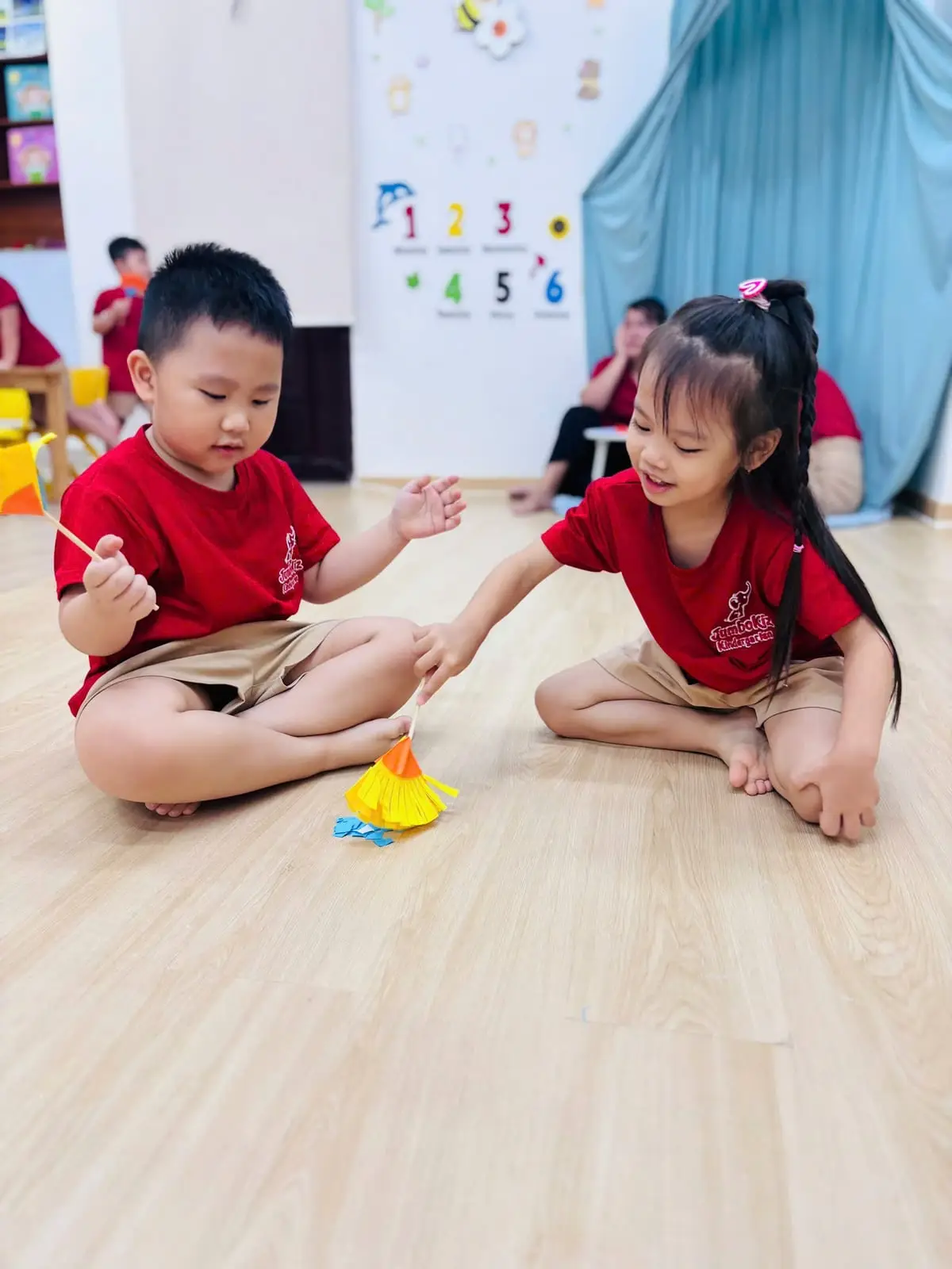 Bé trai và bé gái cùng nhau quét vụn giấy bằng chổi giấy