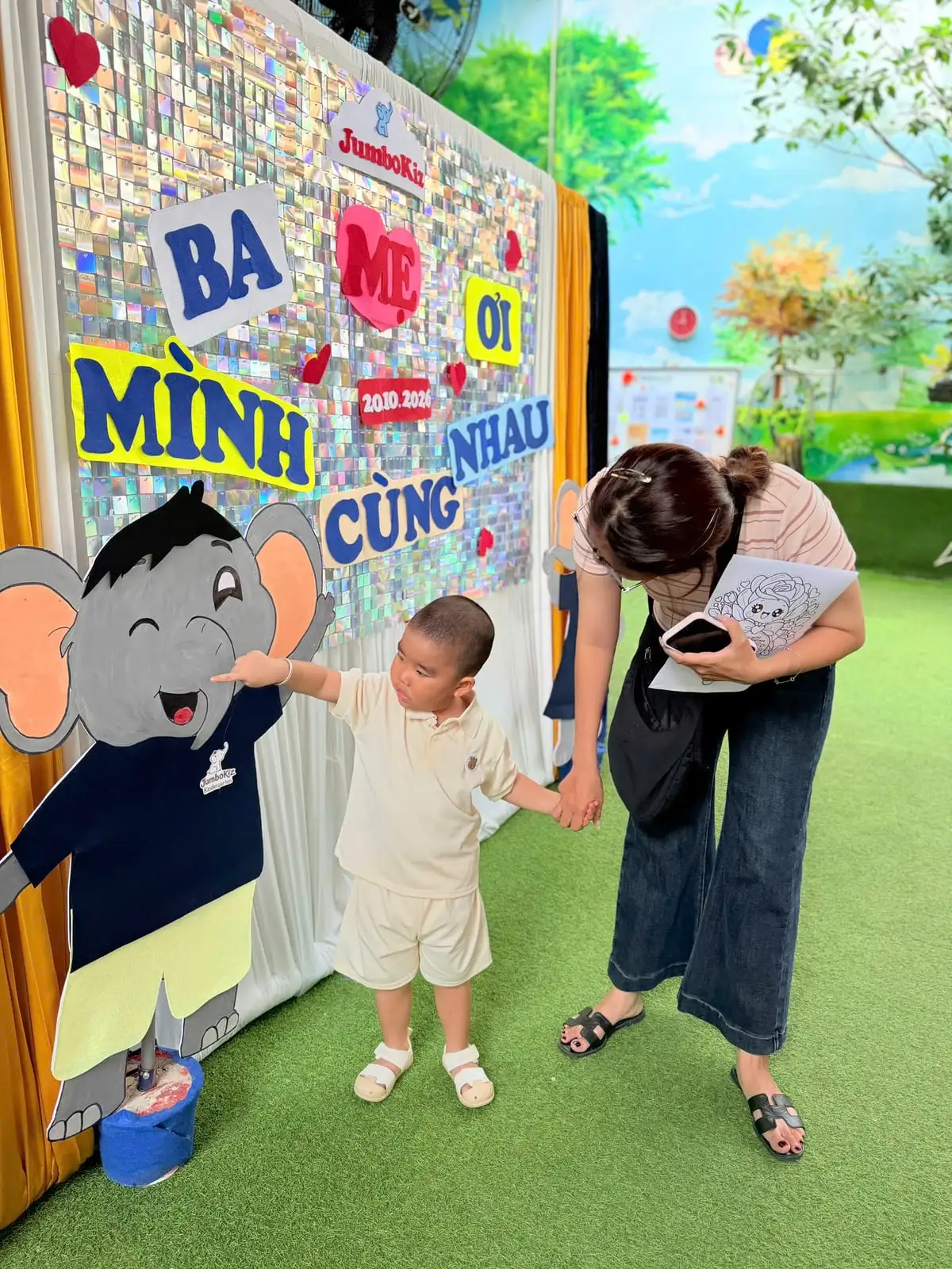 Mẹ nắm tay con trai nhỏ, con chỉ vào chú voi ở sân trường JumboKiz